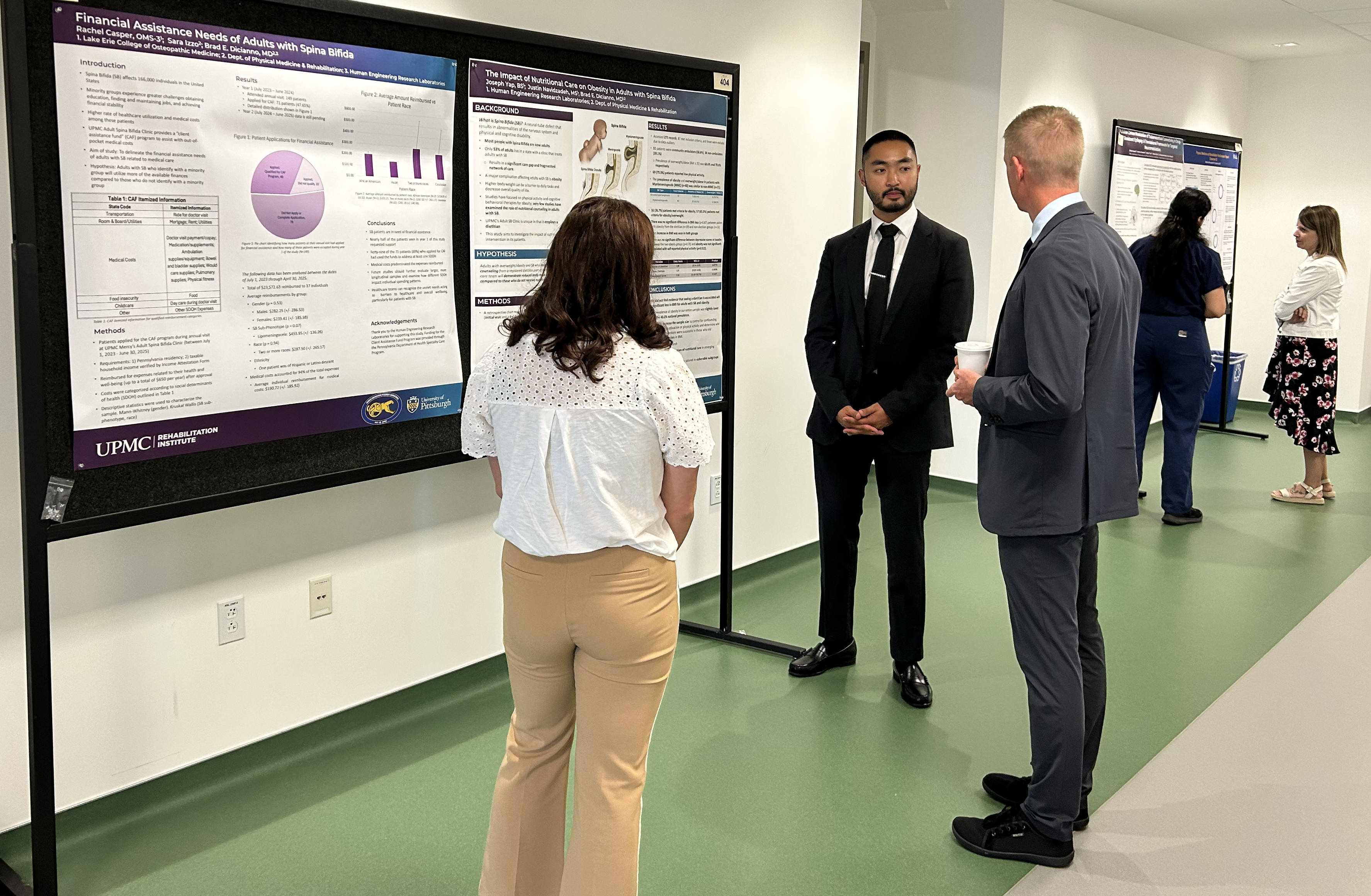 Medical student presenting and speaking about his research poster to two people