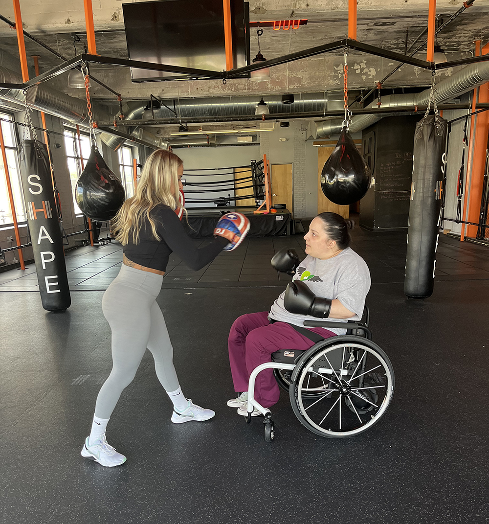 Assistive boxing, individual in a wheelchair boxing with a trainer