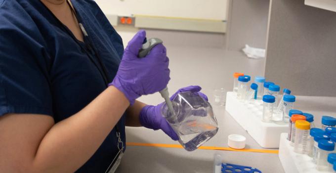 Researcher using a syringe to dispense liquid into a test tube