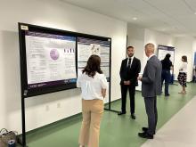 Medical student presenting and speaking about his research poster to two people